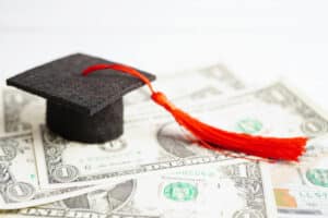 graduation cap on top of dollar bills